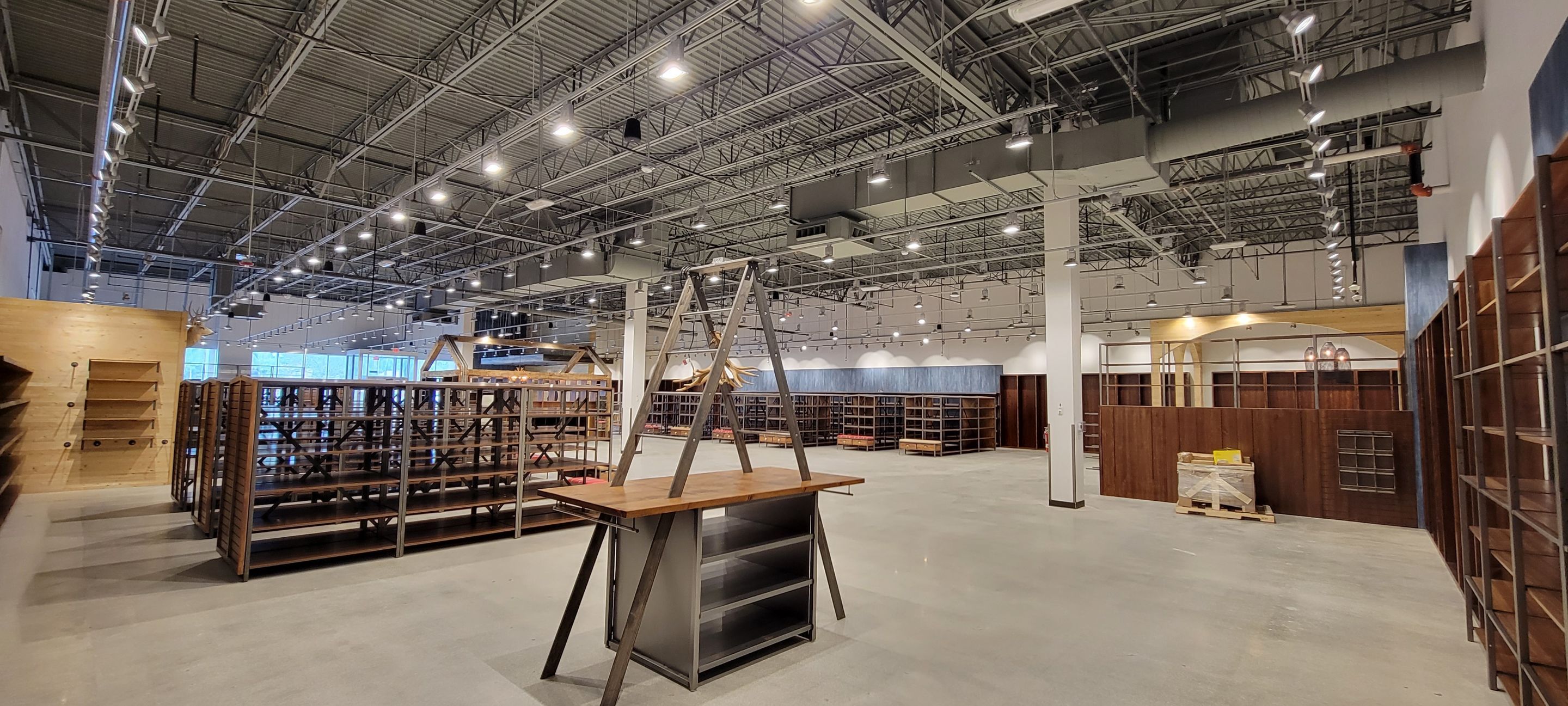 Wide view of a Boot Barn buildout with wood shelving runs, custom millwork, and a polished concrete sales floor
