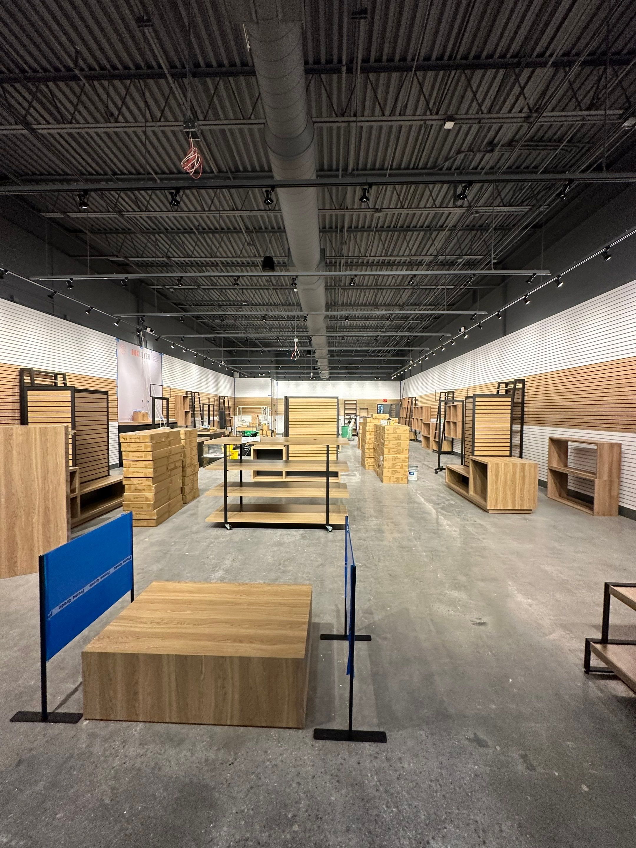 BoxLunch store buildout with wood slatwall fixtures, display tables, and new lighting under installation