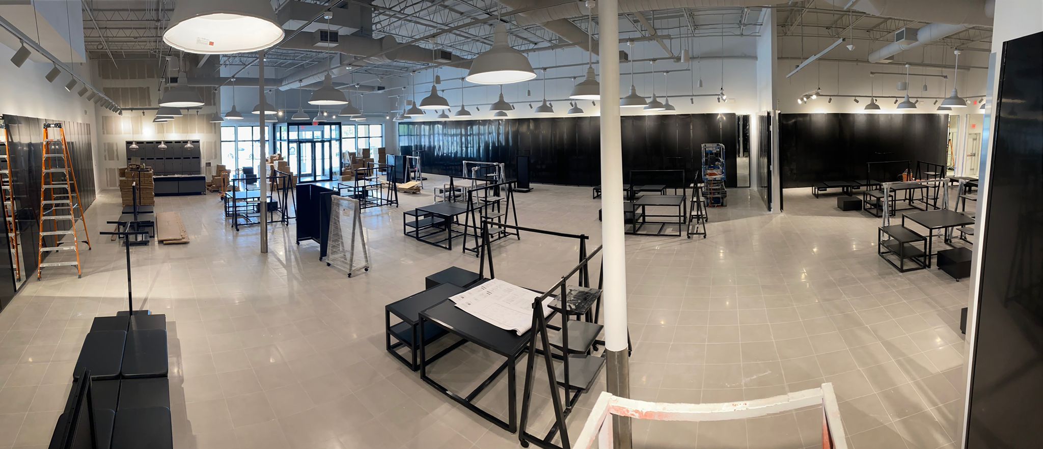 Panoramic view of a Foot Locker sales floor mid-buildout with display tables and lighting installation
